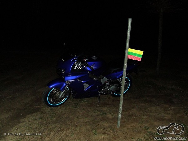 Motociklas prie Lietuvos Respublikos vėliavos kabančios ant stiebo (stiebas - į žemę įkastas dažniausiai metalinis)