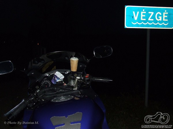 Motociklas ant jo padėta ledų porcija prie KET ženklo: '618. Vandens telkinio pavadinimas, upės, upelio pavadinimas'