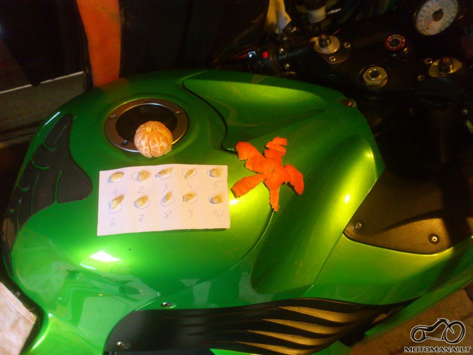 Ant motociklo 10 mandarino (arba apelsino) kauliukų, nuluptas mandarinas bei iš jo žievės padaryta (iškarpyta) žvaigždė